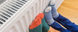 Thema Energie, Füsse in dicke Socken eingepackt am Heizkörper