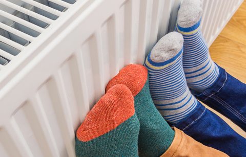 Thema Energie, Füsse in dicke Socken eingepackt am Heizkörper