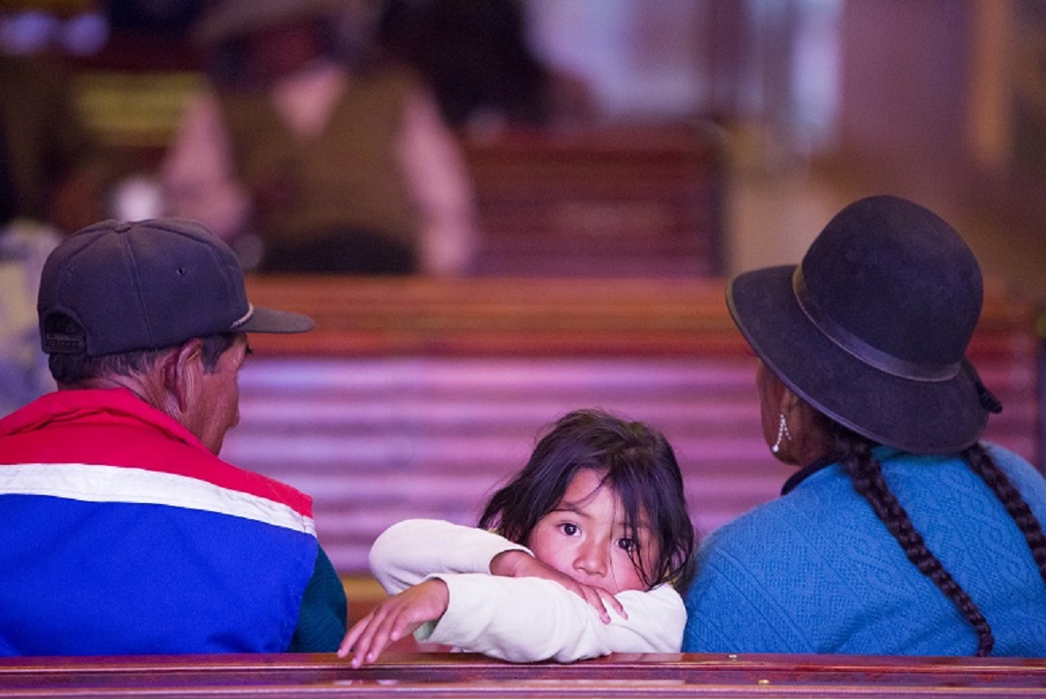 Kleines Inka-Mädchen mit seiner Familie in der Kirche